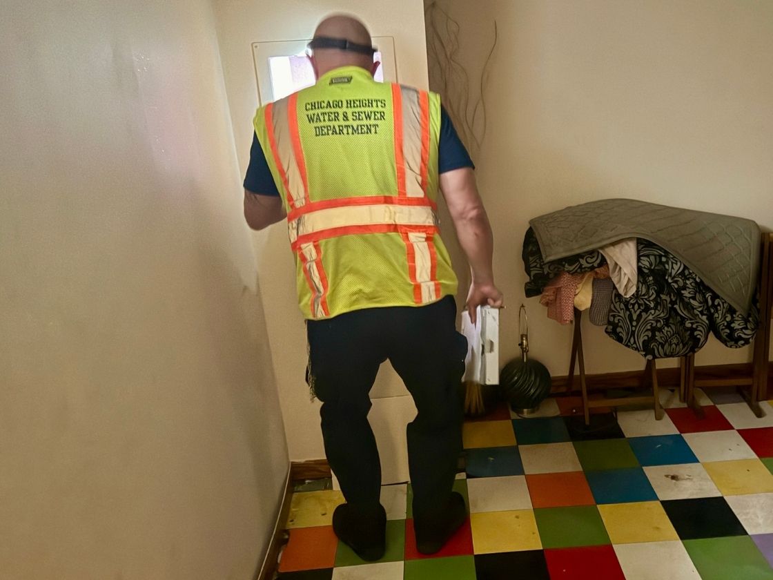 Chicago Heights IL water department worker completing a final water reading in basement of home