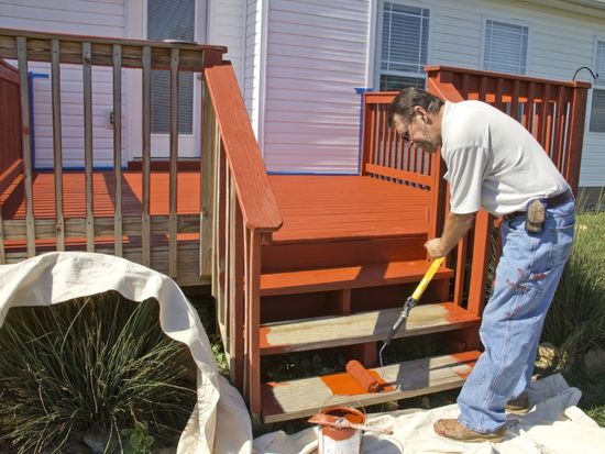man painting deck with roller brush