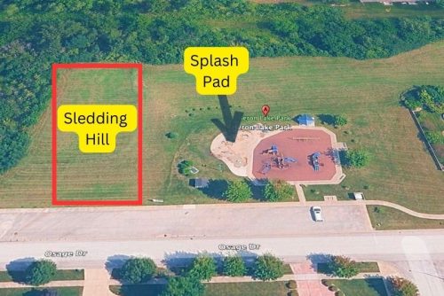 Aerial photo of Heron Lake Park in st John indiana showing the sledding hill, the splash pad, and the playground. The sledding hill and splash pad are labeled