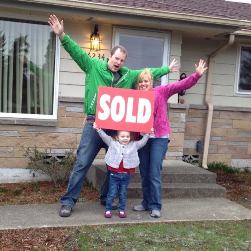 family holding sold sign in front of the home they sold
