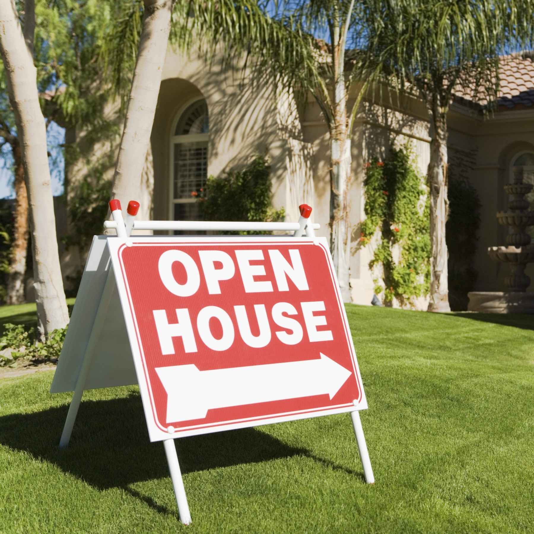 open house sign in a grassy yard pointing to a house