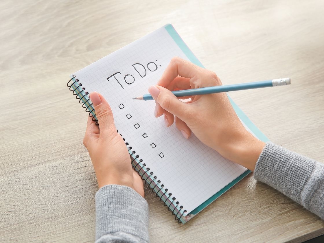 graphic of a "to do" list of a person writing in a notebook with a checklist
